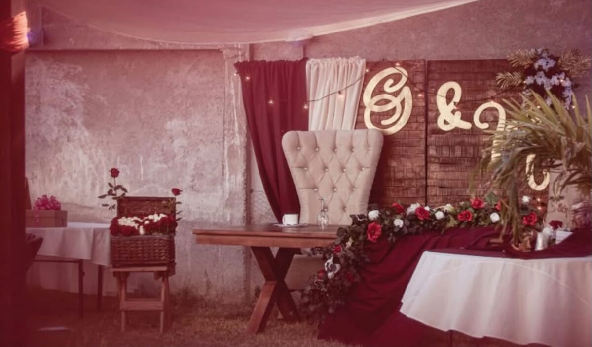 Mesa de honor decorada con flores y cortinaje en tono vino